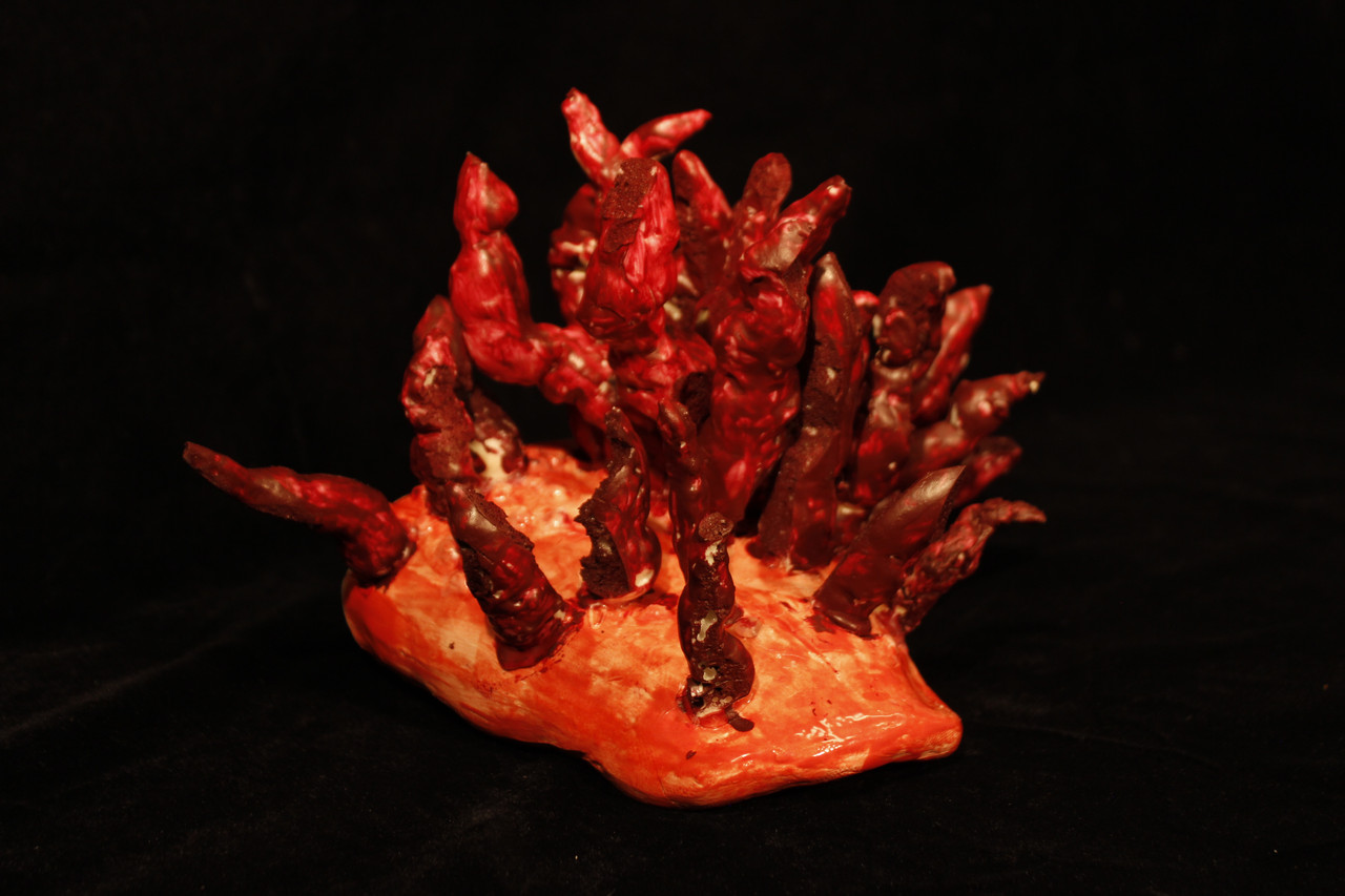 Red sculpture with tongue-like limbs coming out from the base