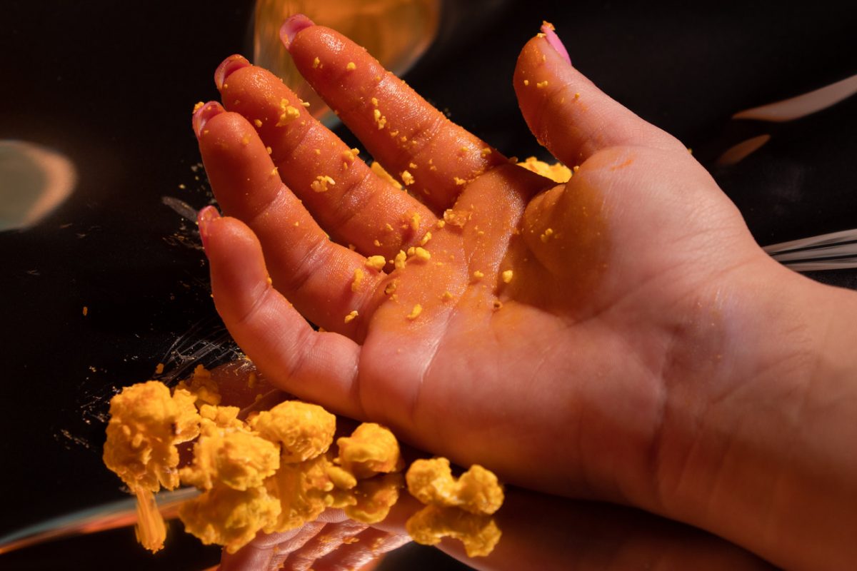 Hand covered in popcorn residue with whole popcorn in the foreground