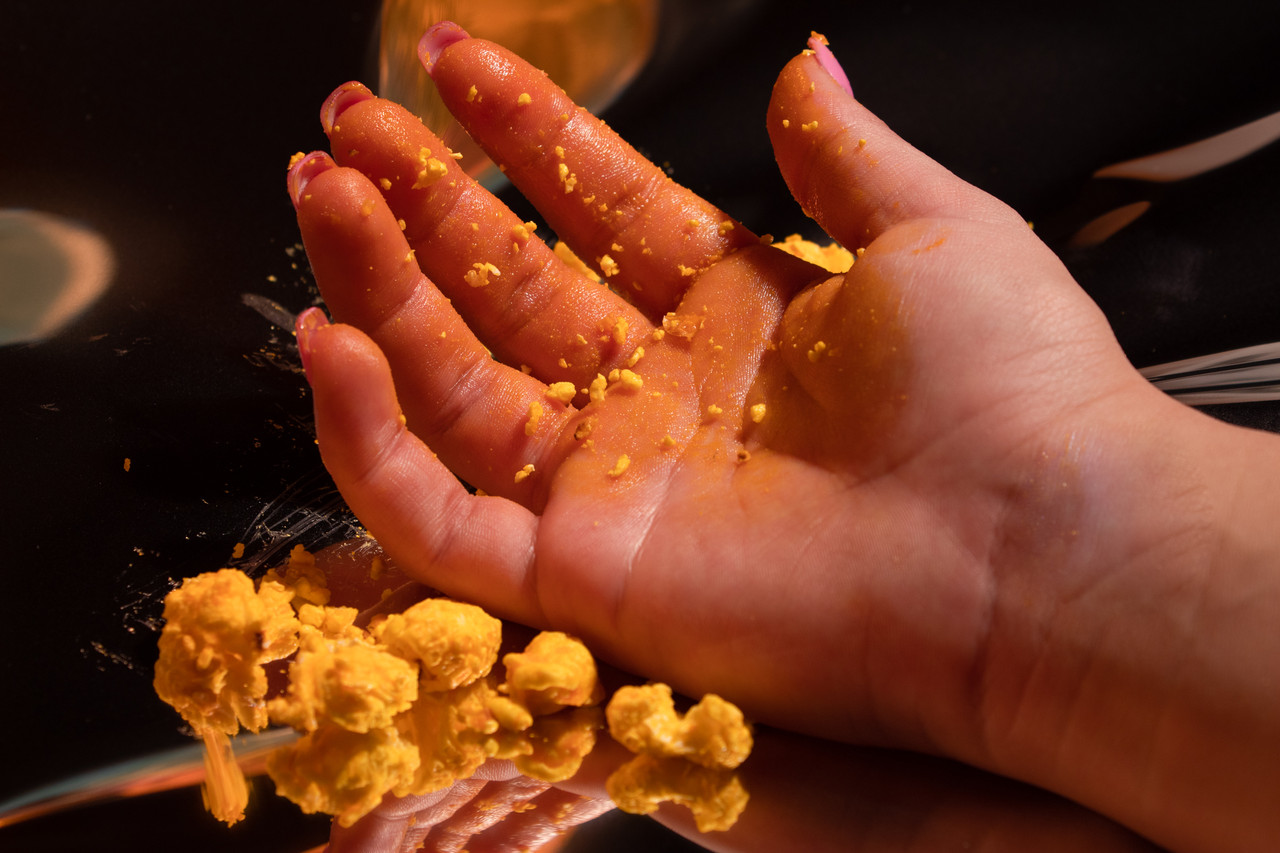 Hand covered in popcorn residue with whole popcorn in the foreground