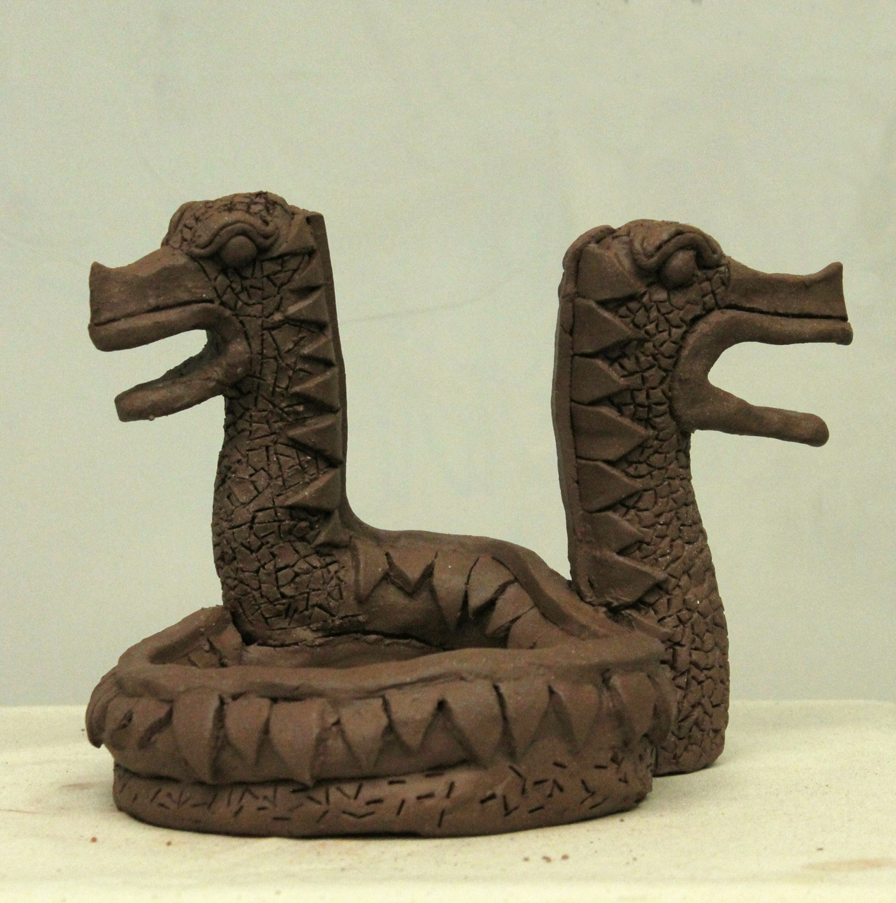 Clay sculpture of two creatures looking opposite directions
