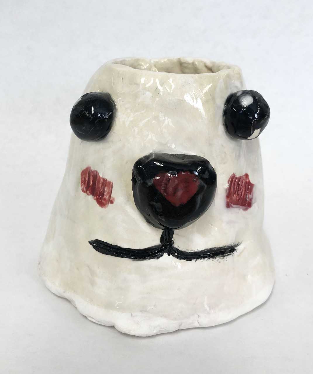 White mug with dog's face with black eyes and nose with a red heart.