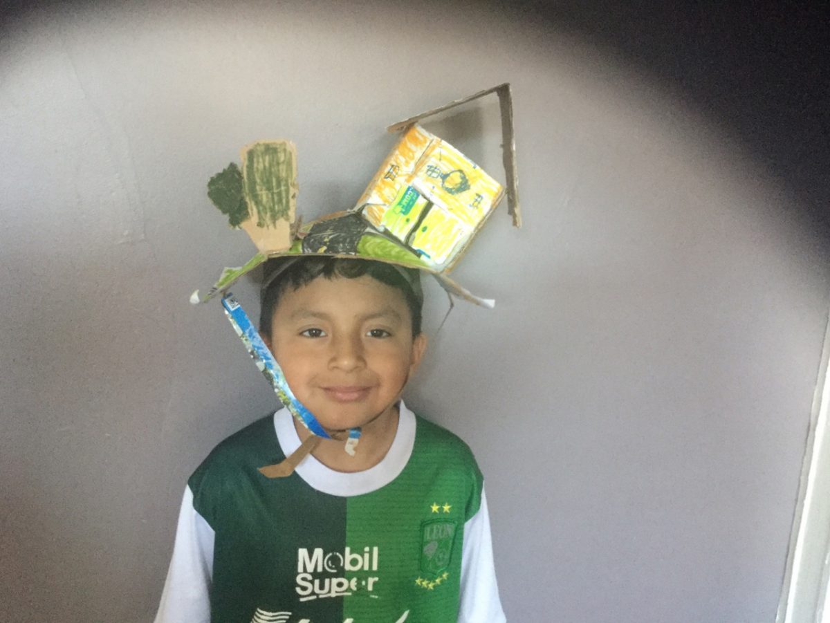 student wearing paper hat with a house