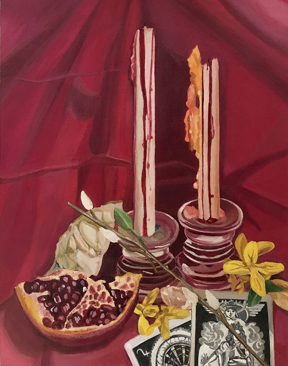 Still life with candles, cards, and pomegranate on red fabric background