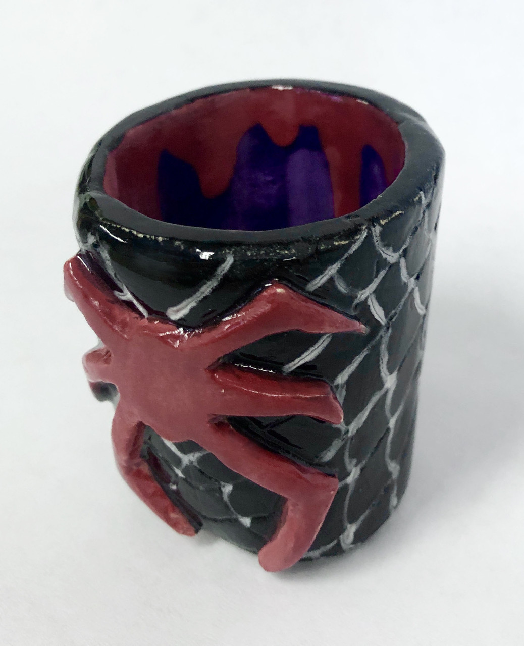 Black ceramic cup with red Spiderman symbol on front, white spiderweb pattern, and red drips on purple interior.