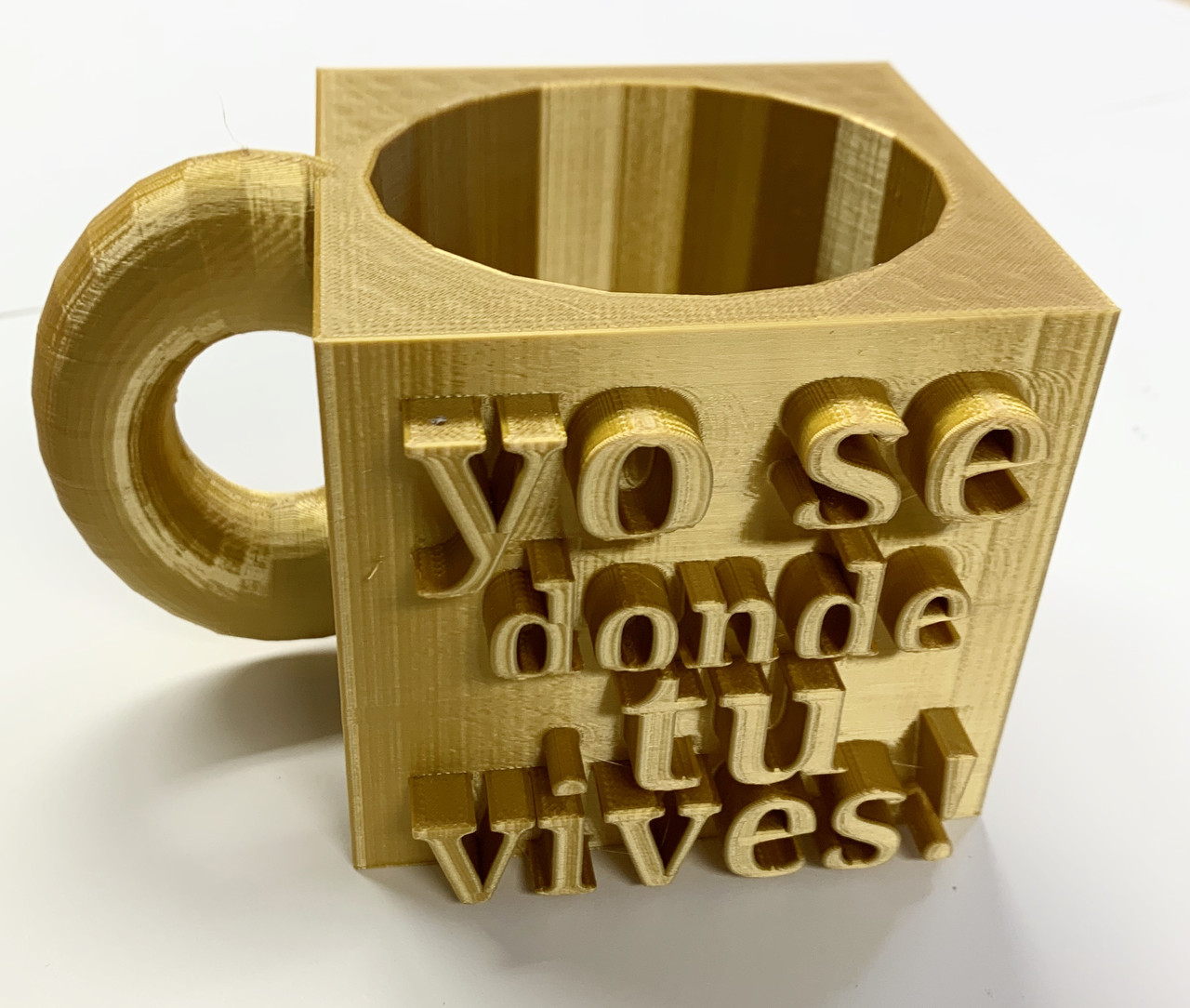 Square, gold cup that says "yo se donde tu vives!"