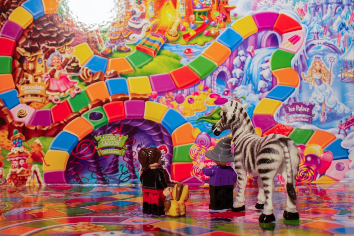 Candyland game board in background with toy figurines in the foreground