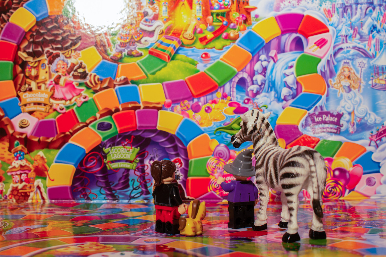 Candyland game board in background with toy figurines in the foreground