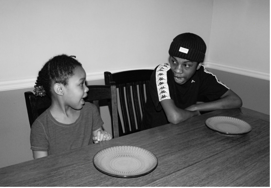 A black and white photograph of two young people sitting at a table