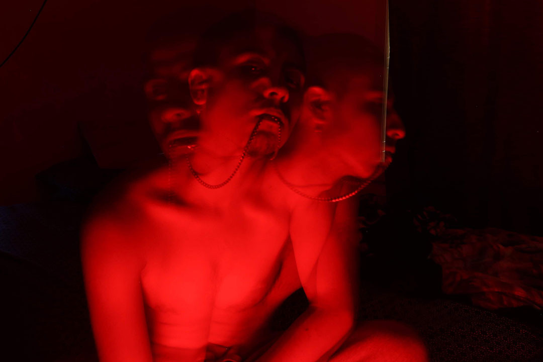 Red light illuminates a figure with multiple heads