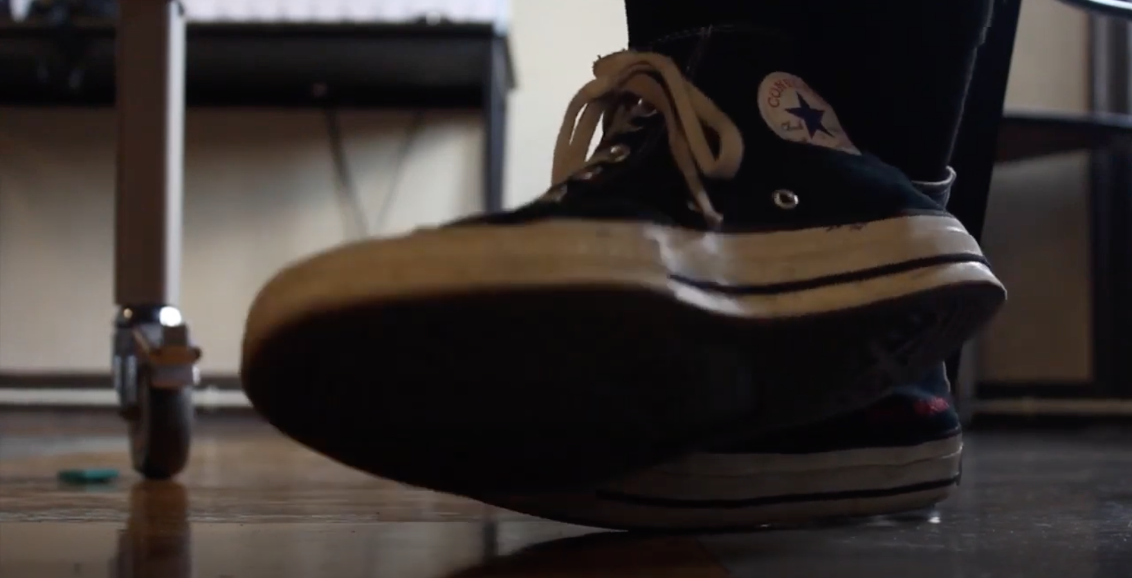 Converse shoes underneath a school desk