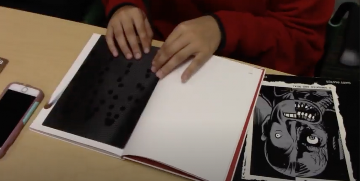 Hands on top of an open notebook on a desk