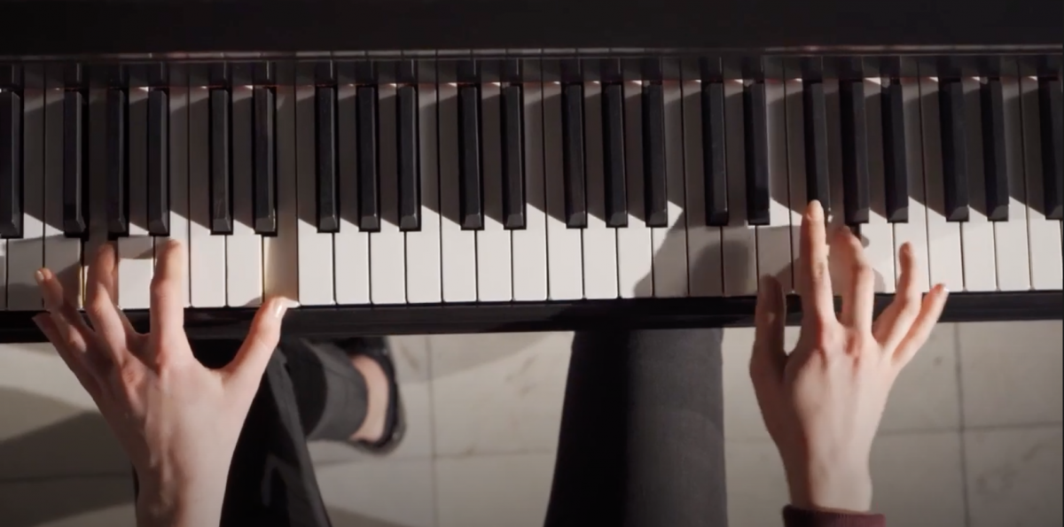 Hands playing a piano from the top down