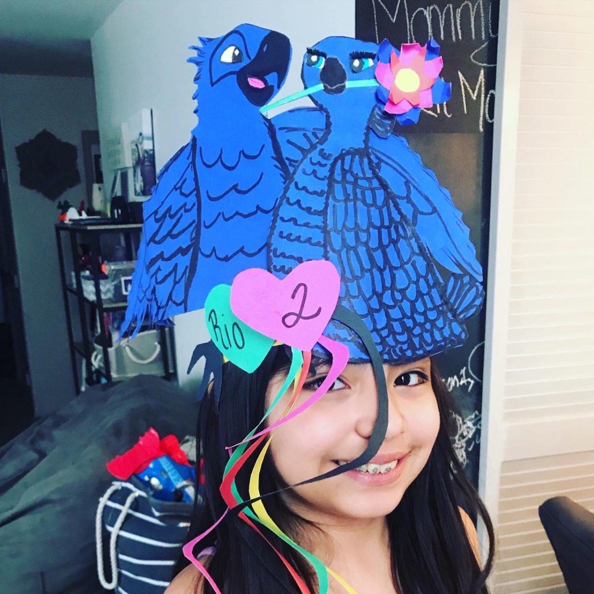 Girl wearing hat with 2 blue parrots from the movie Rio 2