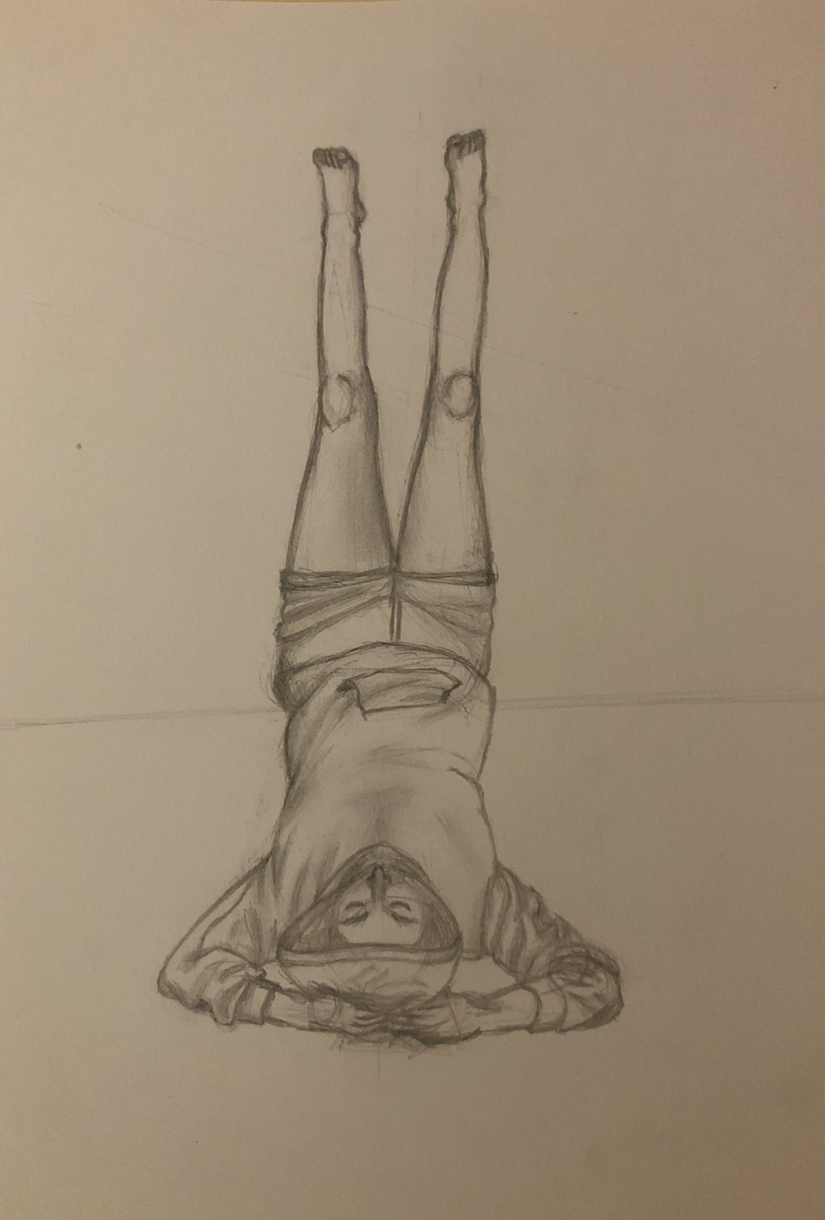 person in hoodie laying with their legs up a wall