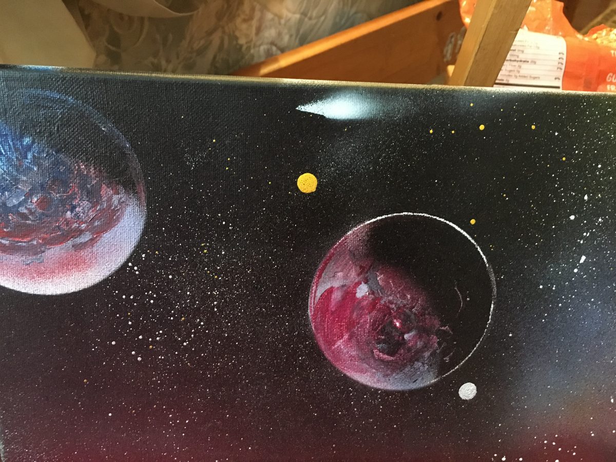 Painting of outer space with two large planets eclipsed half in shadow. Planets are red, white and blue. Yellow and white stars dot the entire canvas.