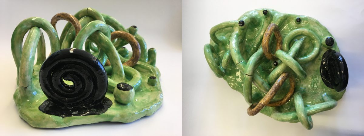 Abstract sculpture featuring black spiral pattern, eyeball-shaped spheres with black dots and loops of green material tangled on top