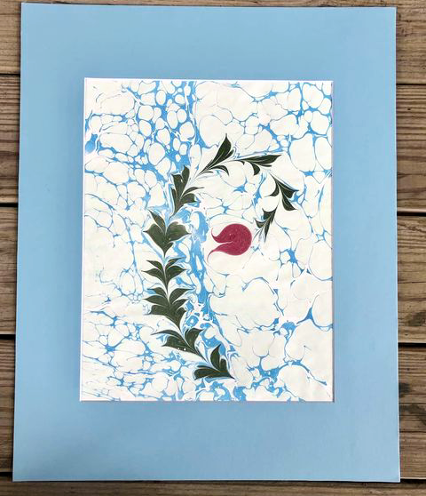 Water marbled painting of a red rose curling into a slight spiral.