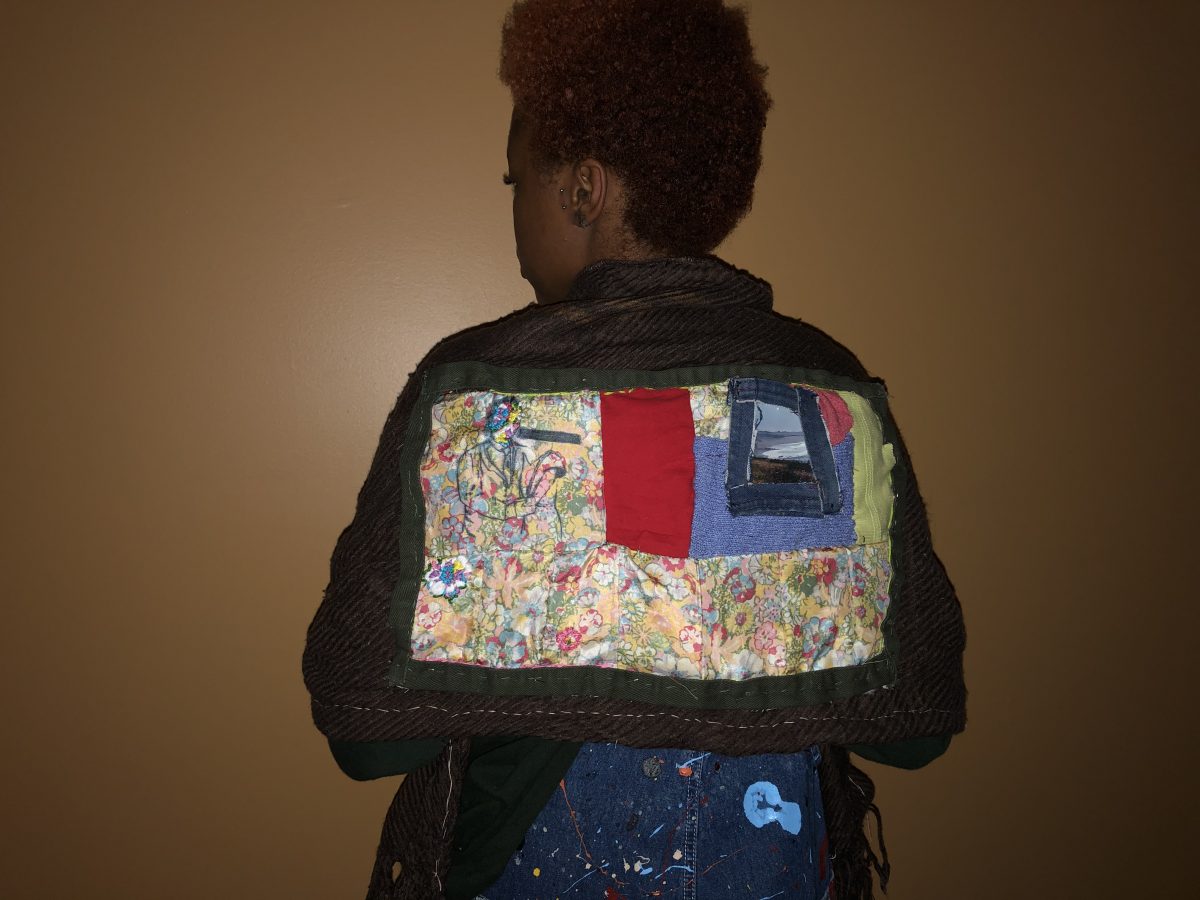 Photograph of person standing with back turned to camera, wearing a shawl made by artist