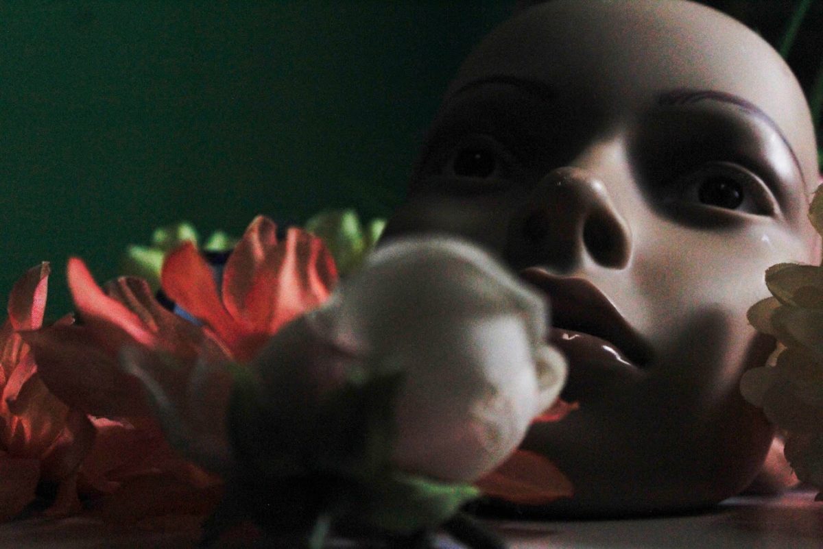 Dramatically lit still life of flowers and a mask.