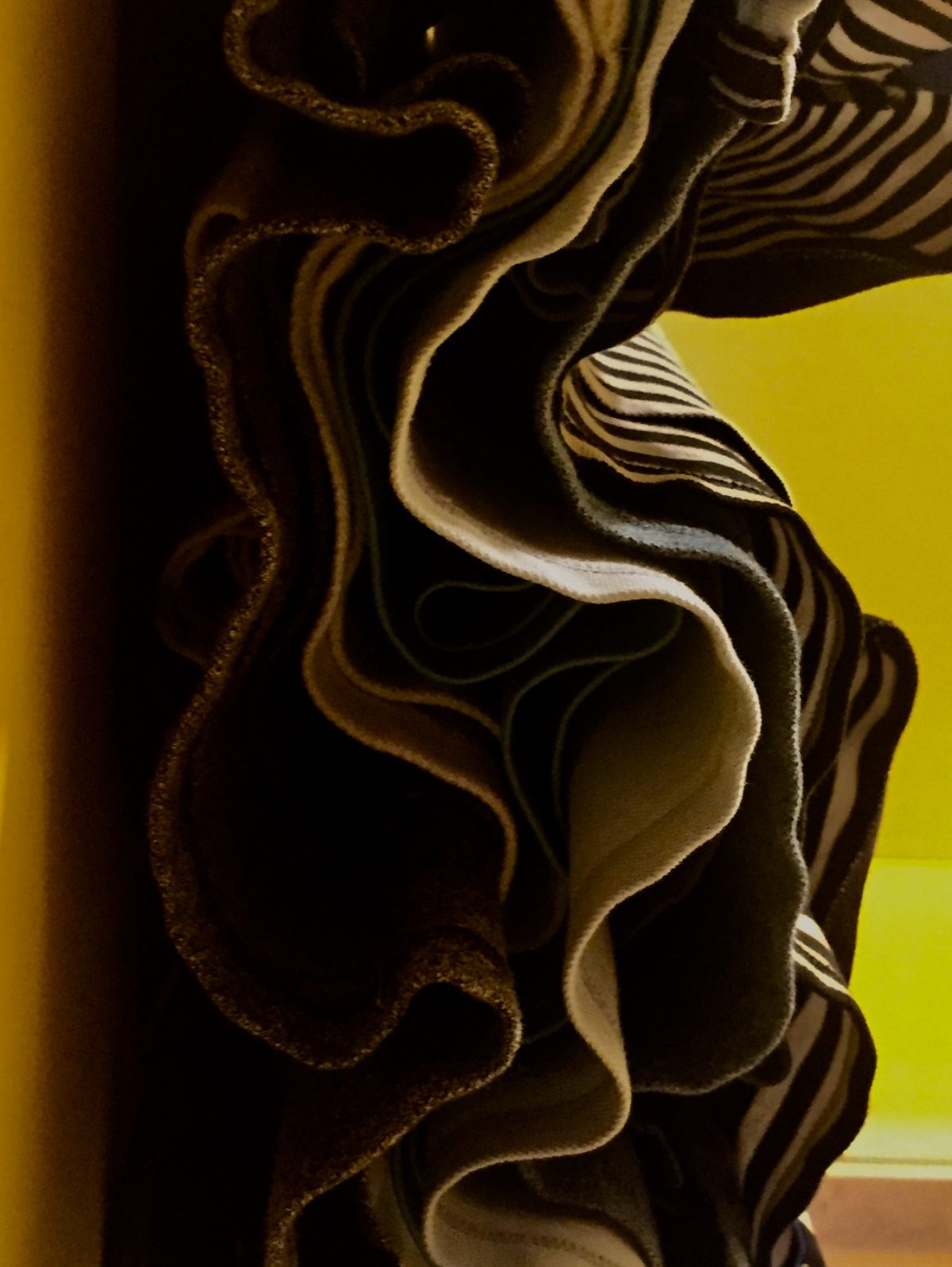 Photography of clothing oriented 90 degrees to the right. The clothes create flowing wave-like lines across the image.