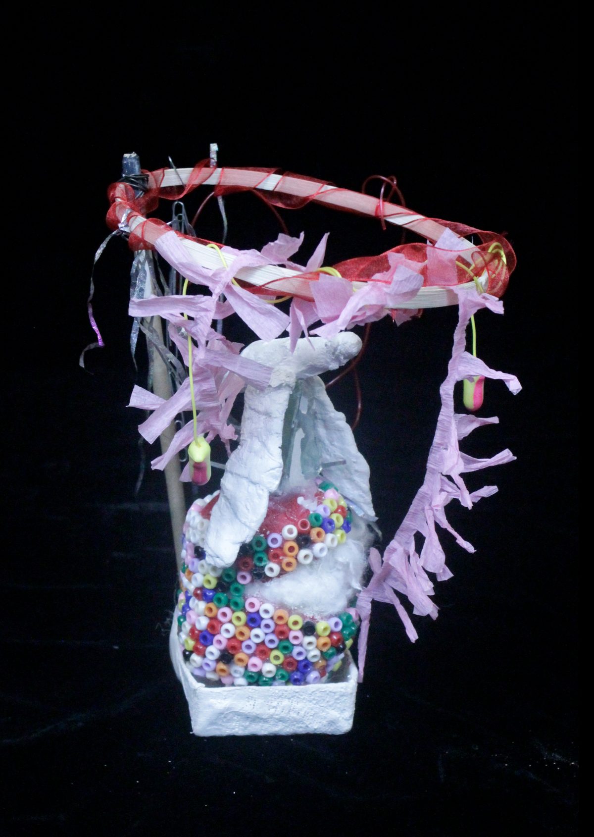 Abstract sculpture with white plaster base, rising up with wire, colorful plastic beads, ribbon and paper.