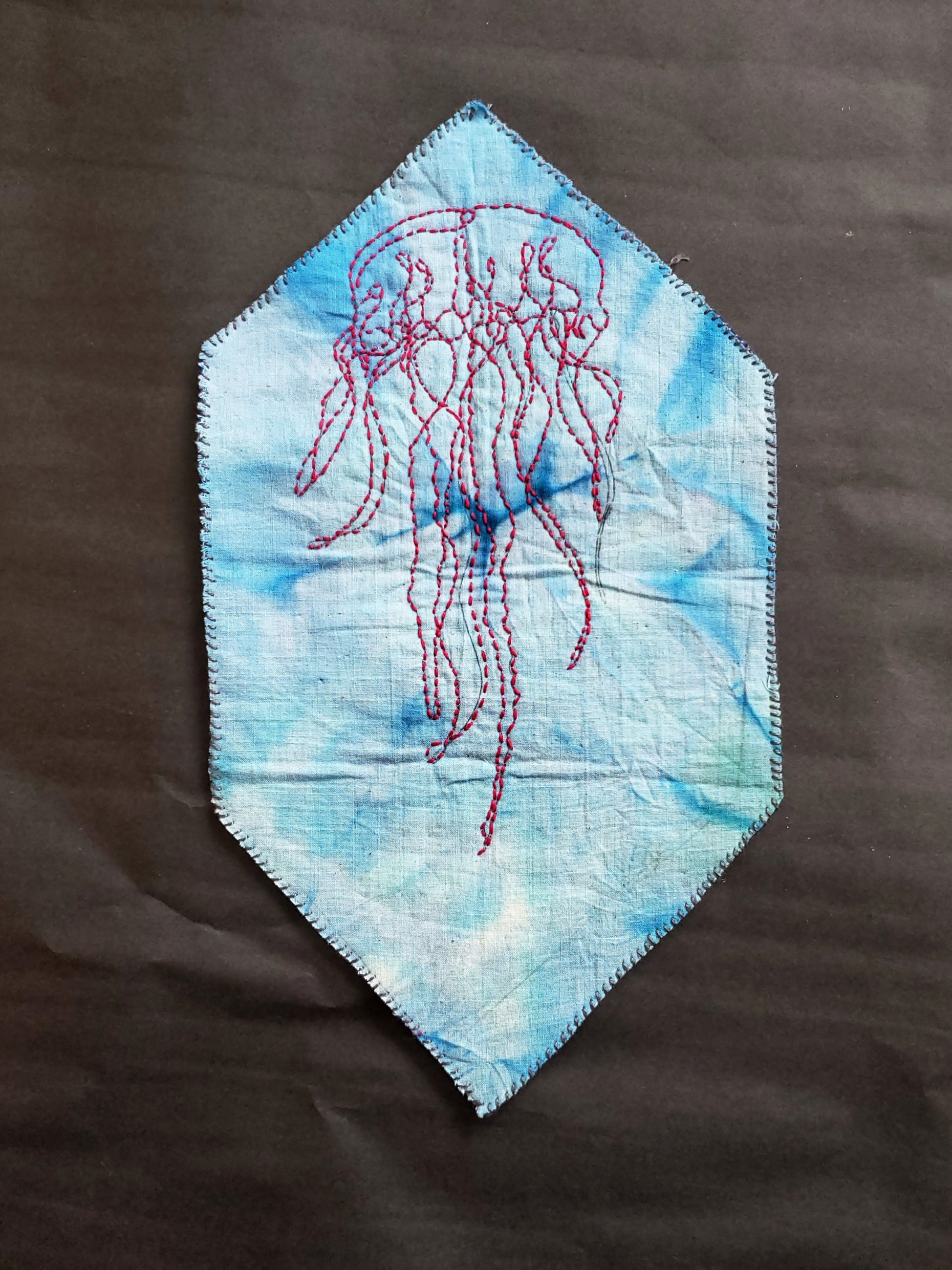 Jellyfish line pattern stitched in a swatch of blue cloth.