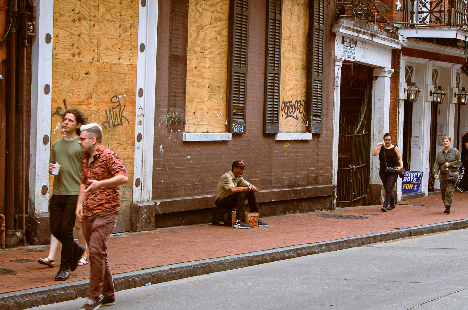 People walking along street past boarded up windows
