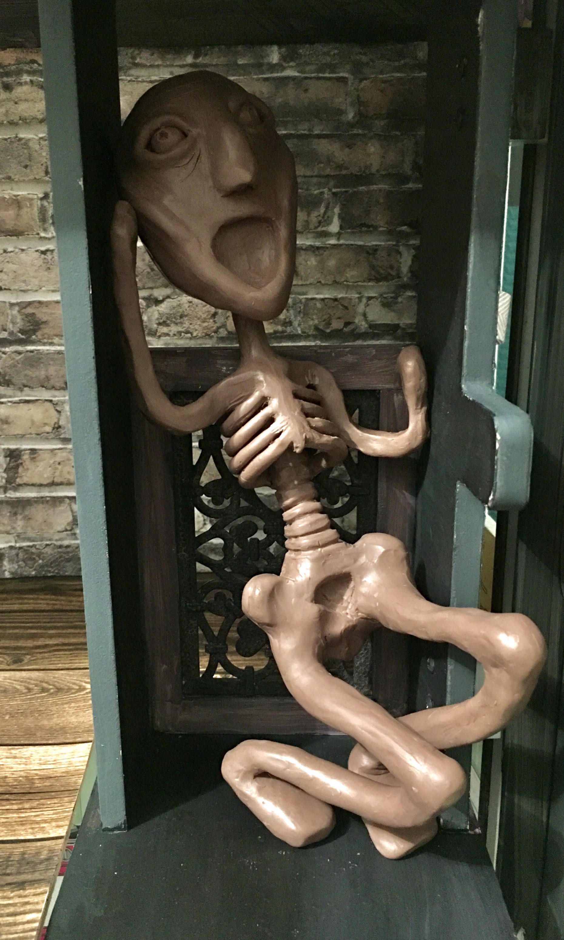 Skeleton like sculpture in a green box, screaming.