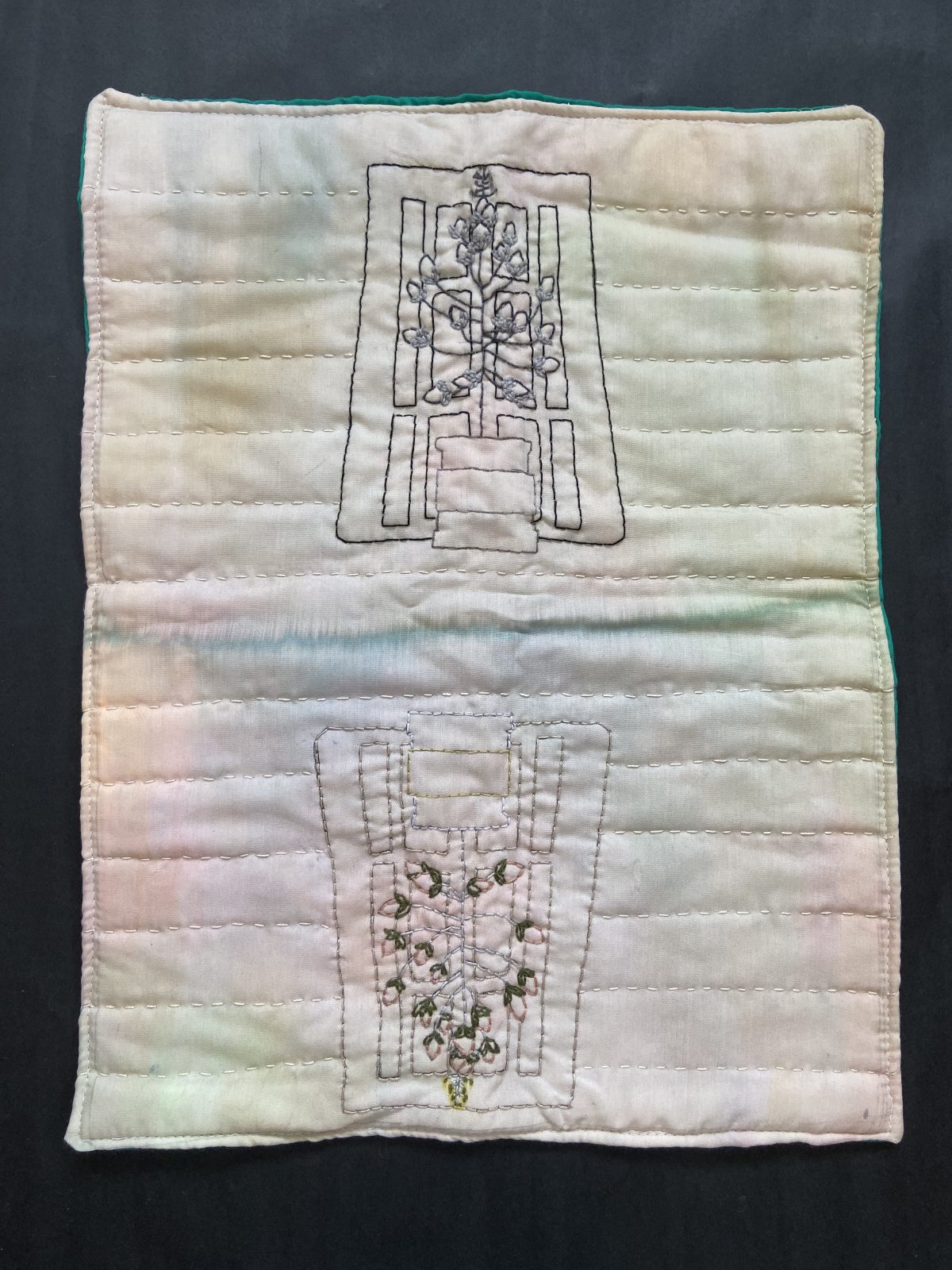 Embroidery of a doorway with tree, reflected vertically on quilt.