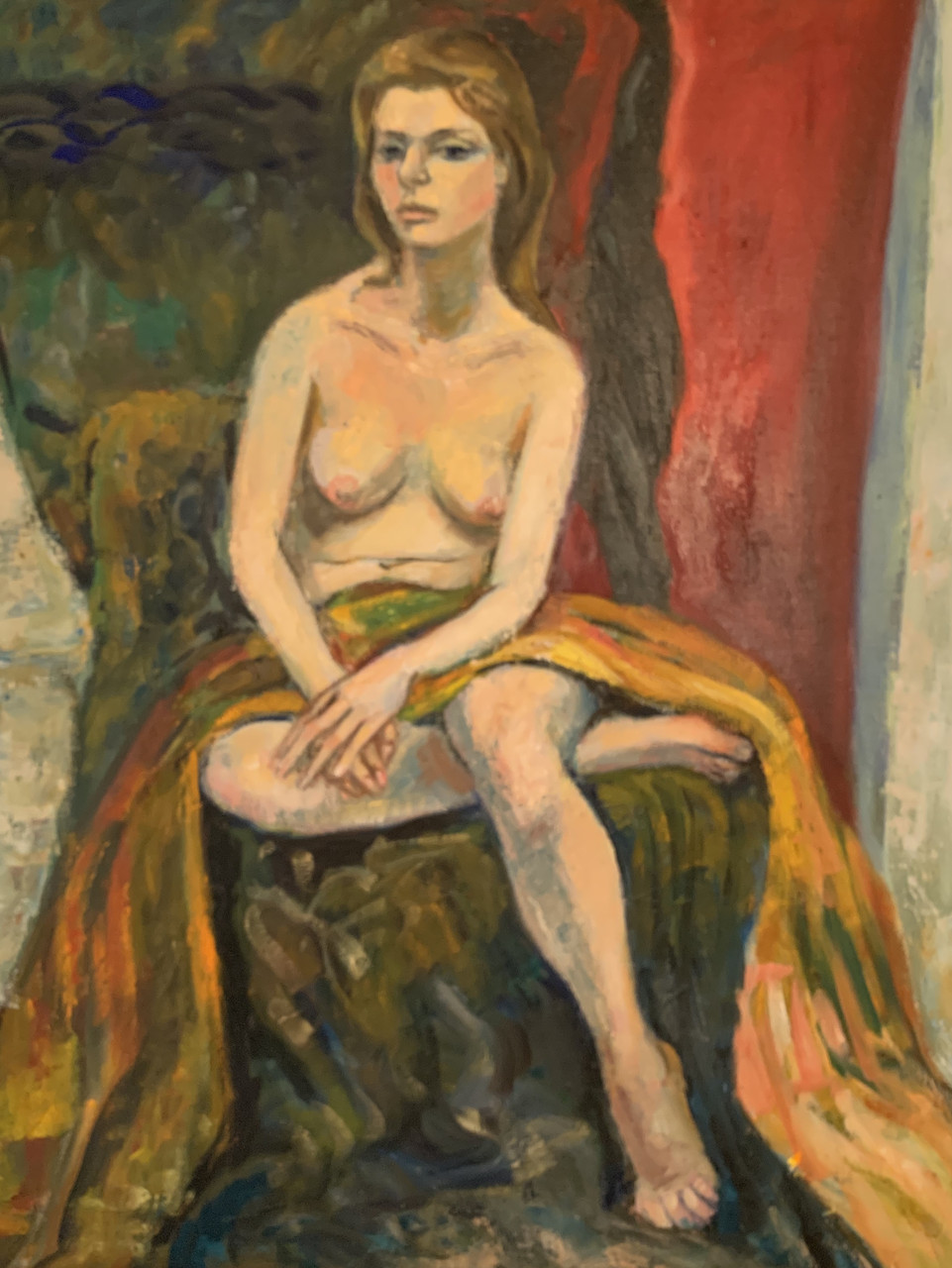 Nude woman sitting on chair draped with fabric. Fabric is draped across her waist.