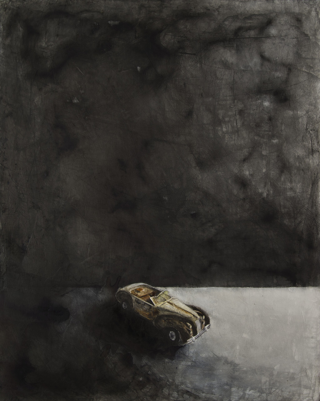 Small, cream, toy car in a dark space.