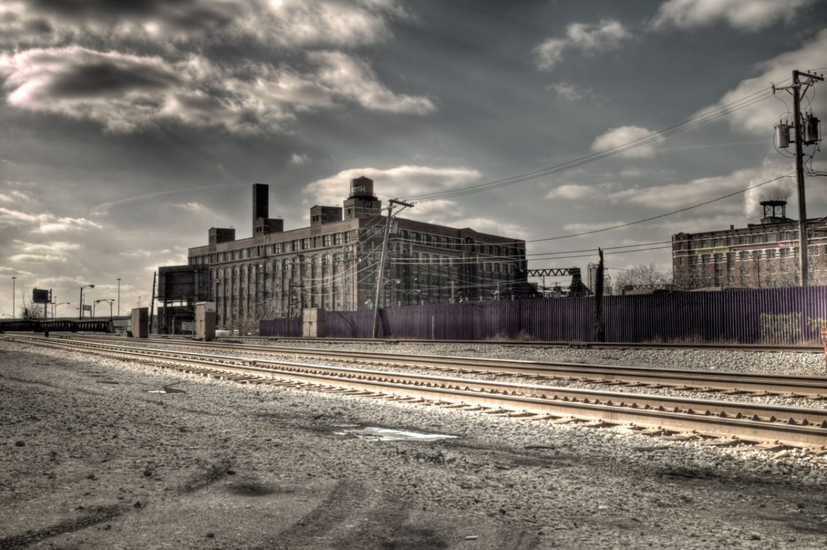 Photograph of train tracks in front of old industrial building.