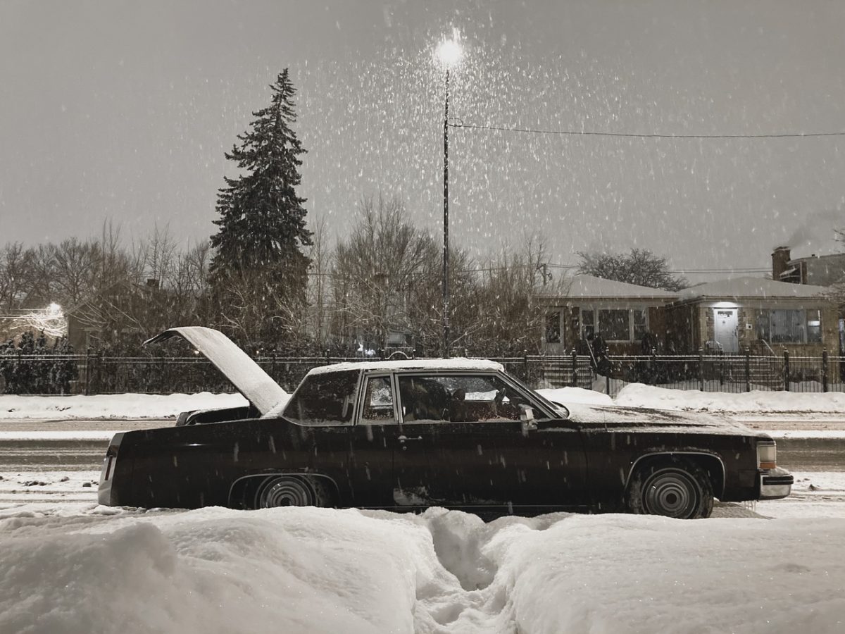 A black and white photo of a car in the snow with the trunk open