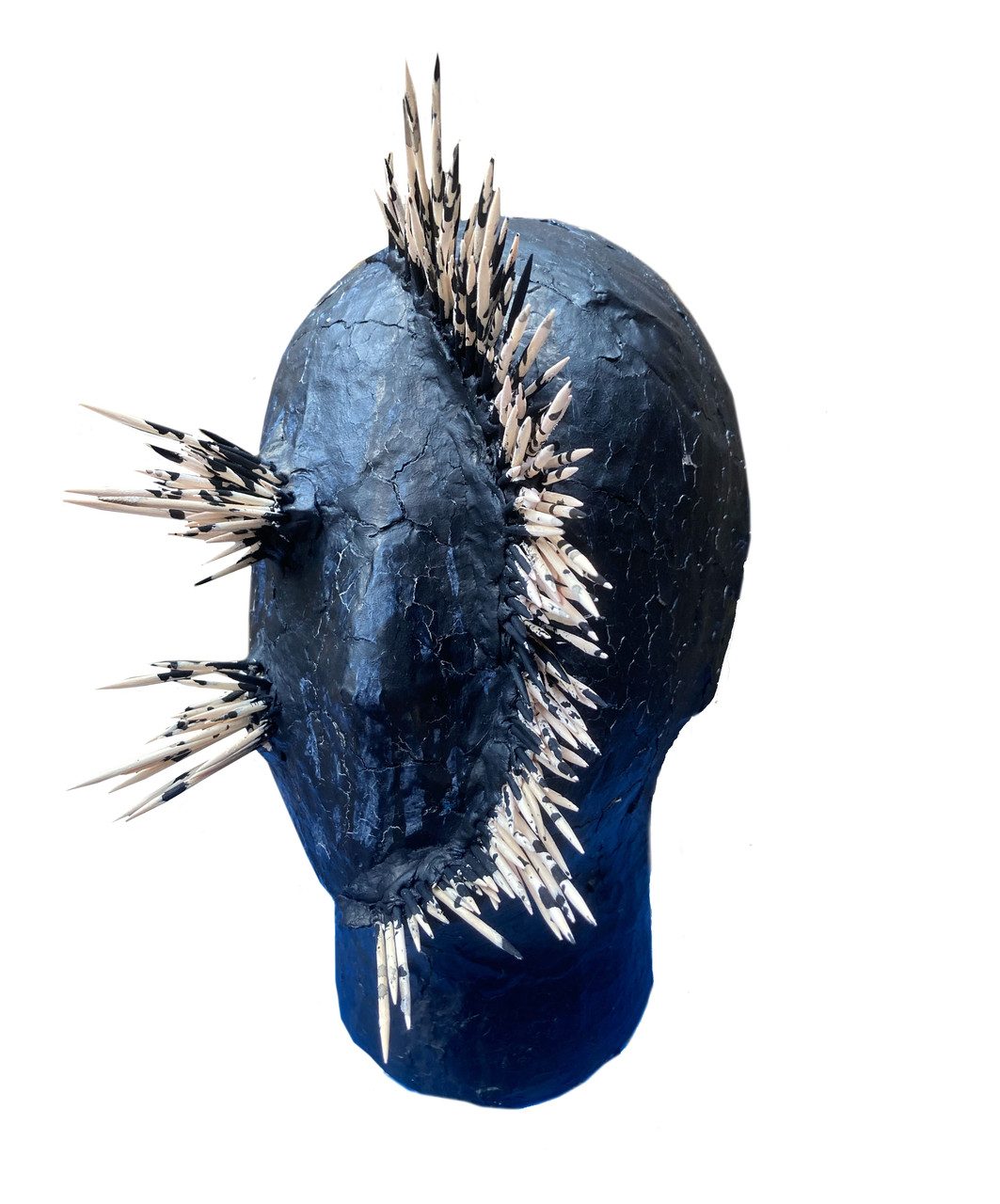 A mixed media sculpture of a mannequin head with wooden spikes coming out of the face