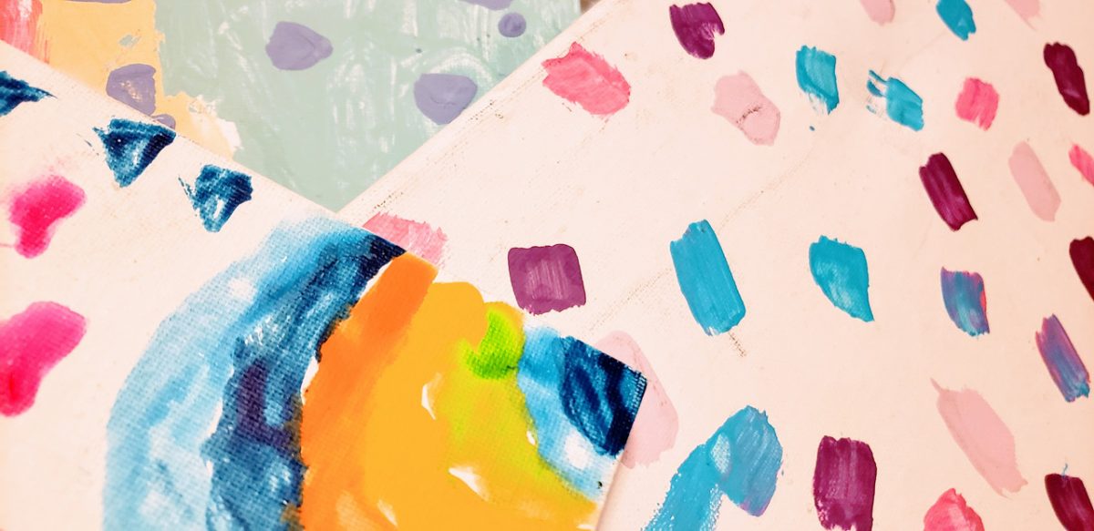 Colorful abstract drawing with many dots of color in the background and a rainbow in the foreground