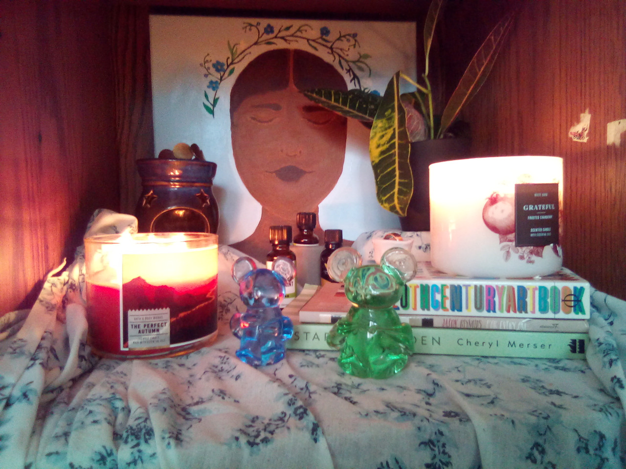 Installtion with a candle, a picture of a girl and some figurines