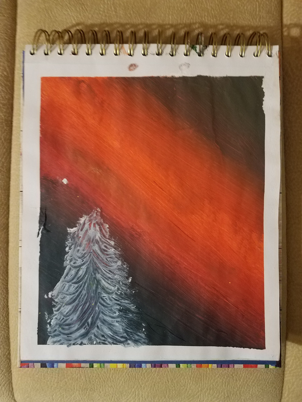 Sketchbook with pine tree drawn in pencil with orange streak behind it