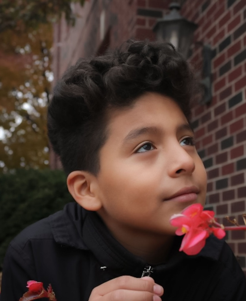 Photograph of a boy holding a red flower