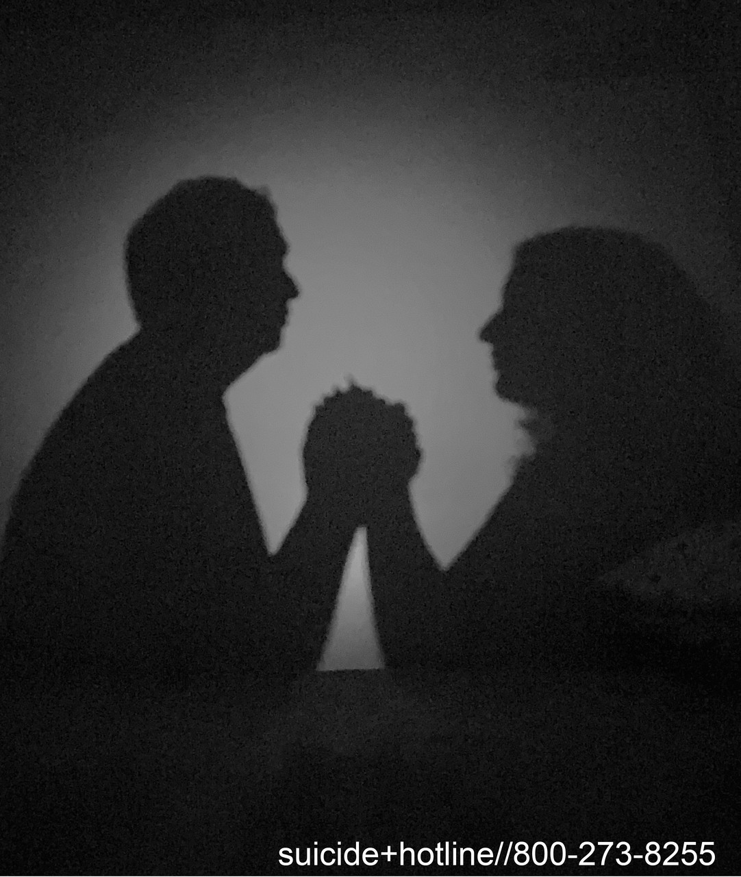 A black and white photo of two peoples shadows holding hands
