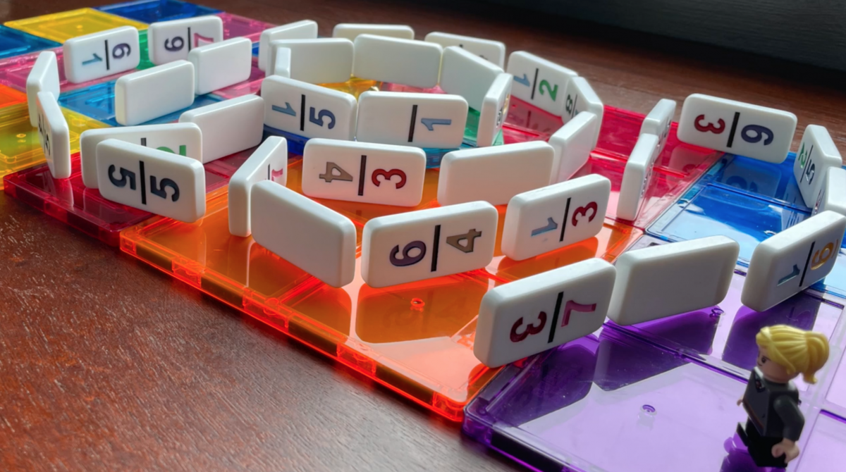 dominoes on edge on platform of magnatiles, with lego figurine next to dominoes.