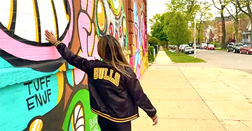 person in black bulls jacket touching painted wall