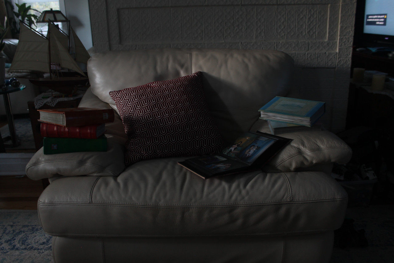 Dark photograph of a chair with pillows