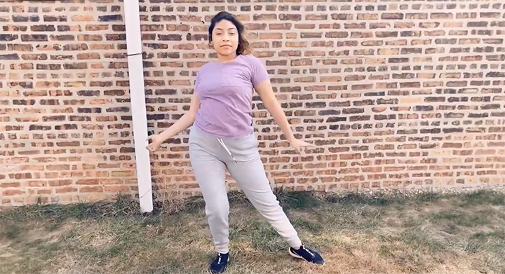 person in purple shirt in front of brick wall