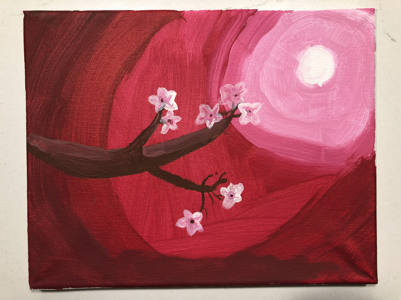 Painting of cherry blossom branch against a red and pink sky