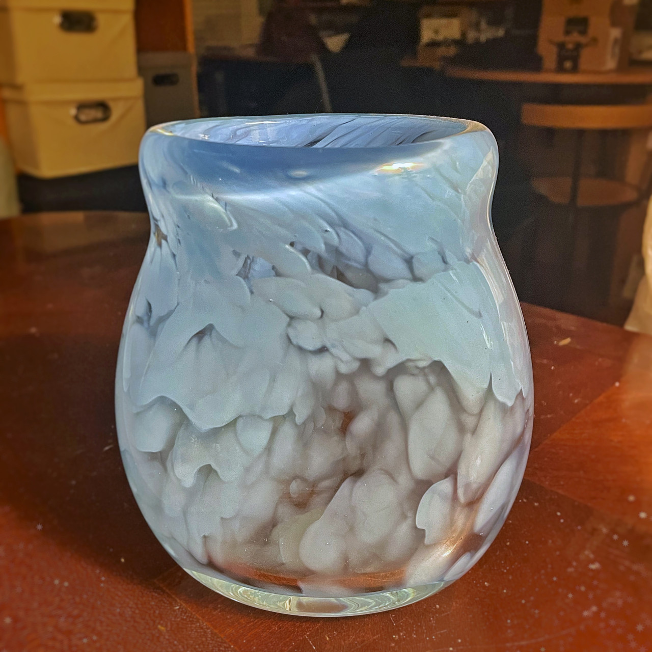 A hand blown glass vessel with a white and light blue pattern