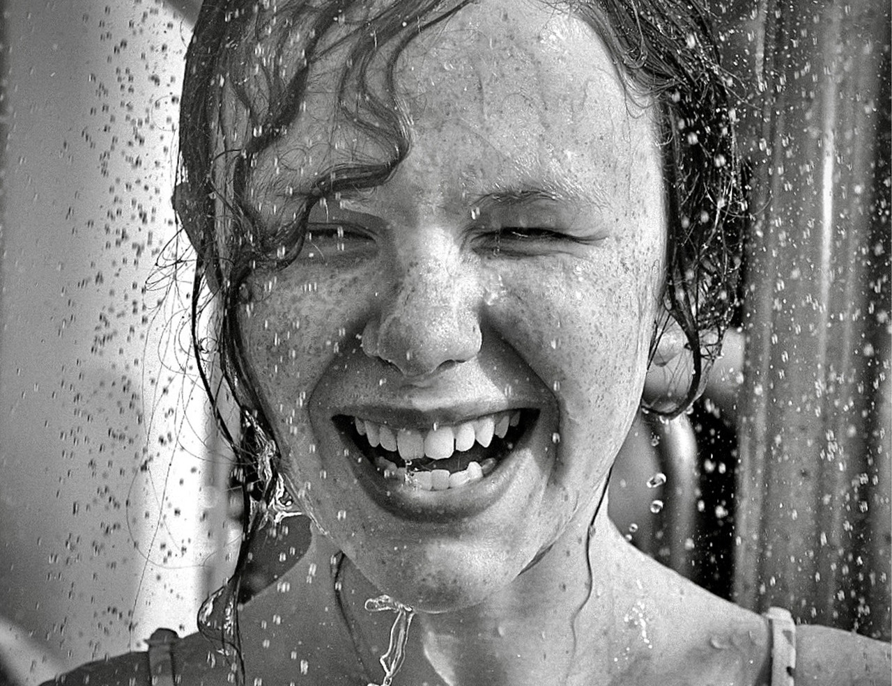 photograph of a young woman smiling in a rainfall