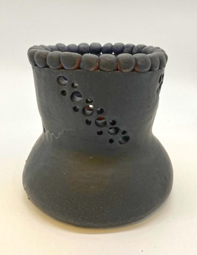 Black ceramic piece tapering at the top with holes in it