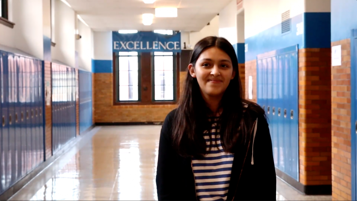Photo of a person standing in a hallway under an "excellence" banner