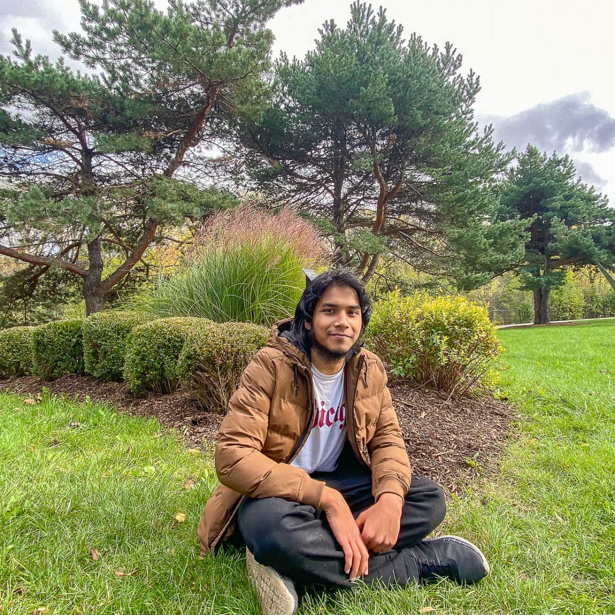 self portrait photograph of a student seated amongst the trees in a grassy spot