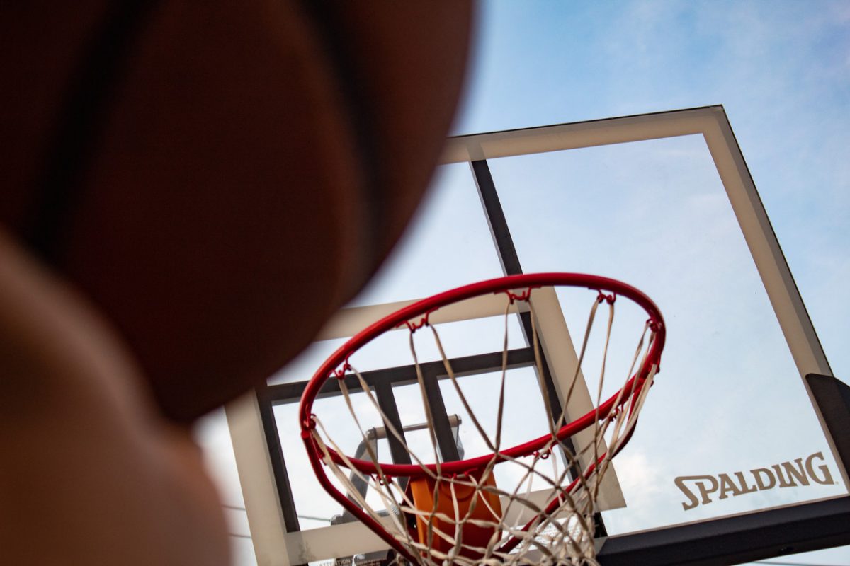 a photograph of an over the shoulder perspective of a basketball being shot into a basketball hoop